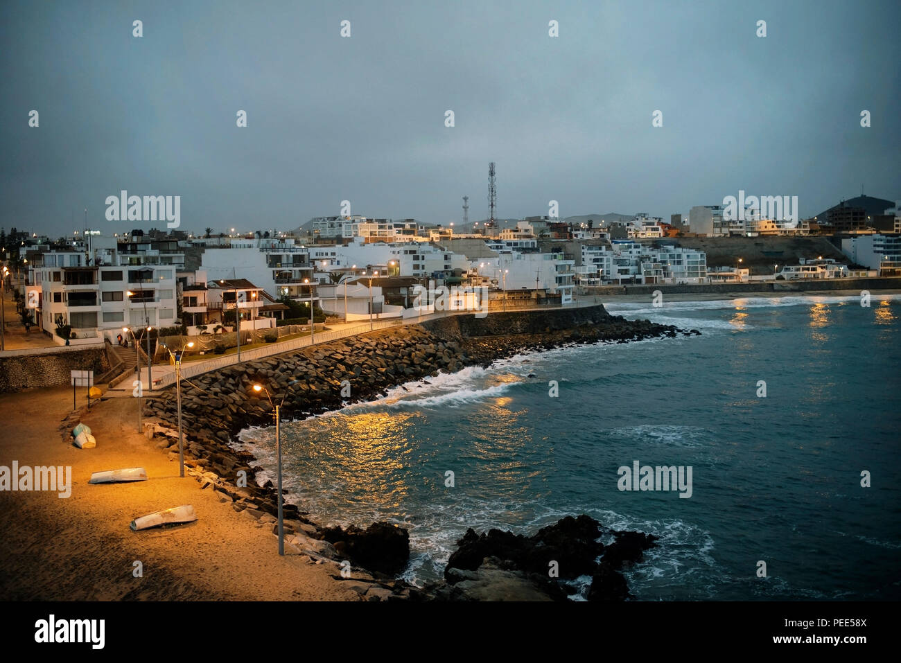 Beachfront and evening lights in Punta Hermosa surfers town, viewed from 'La Isla' (rocky island joined to the land). Lima Province, Peru. Jul 2018 Stock Photo