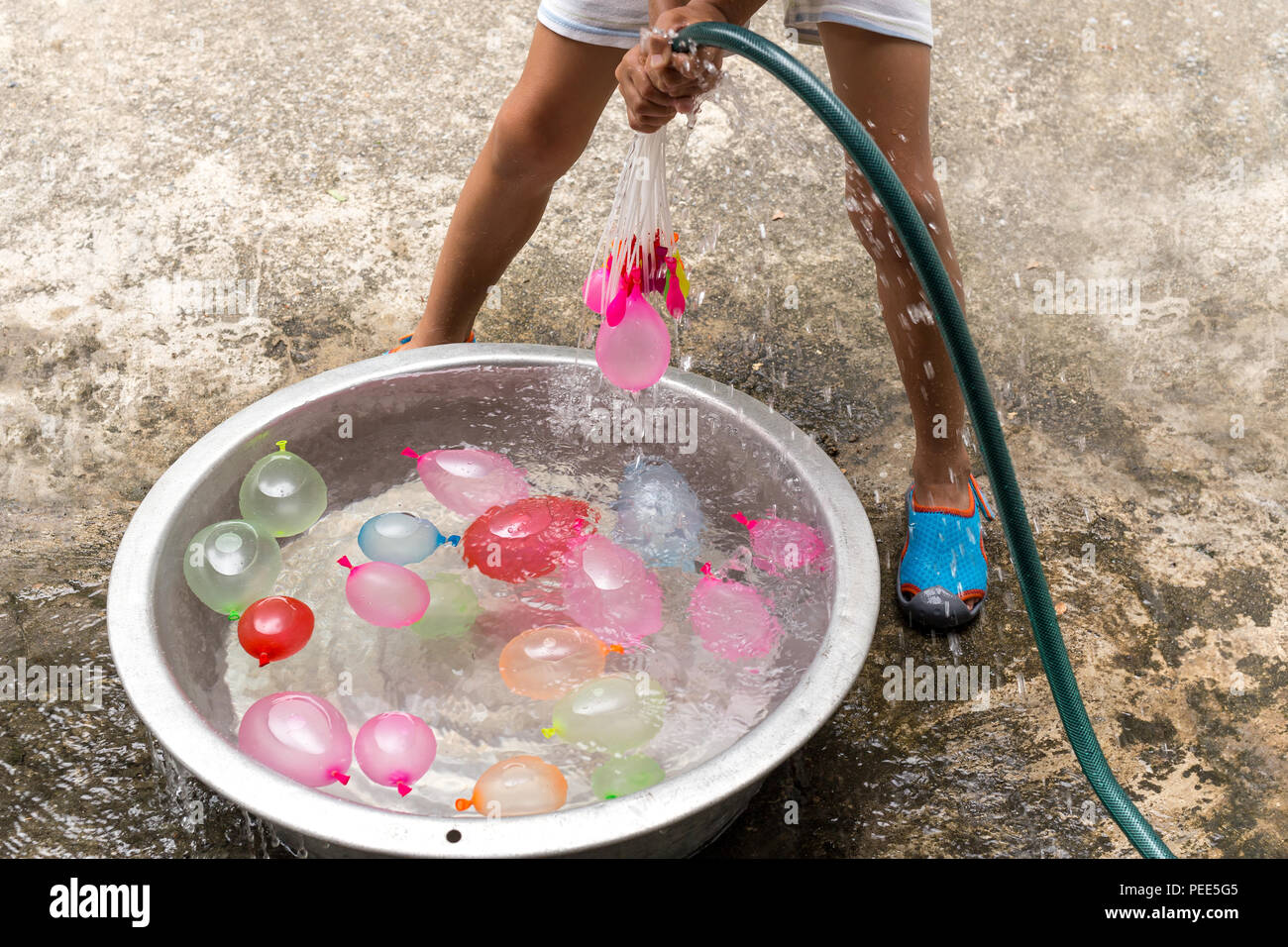 Little boy with water hose filling colorful water balloons in bucket Stock Photo Alamy