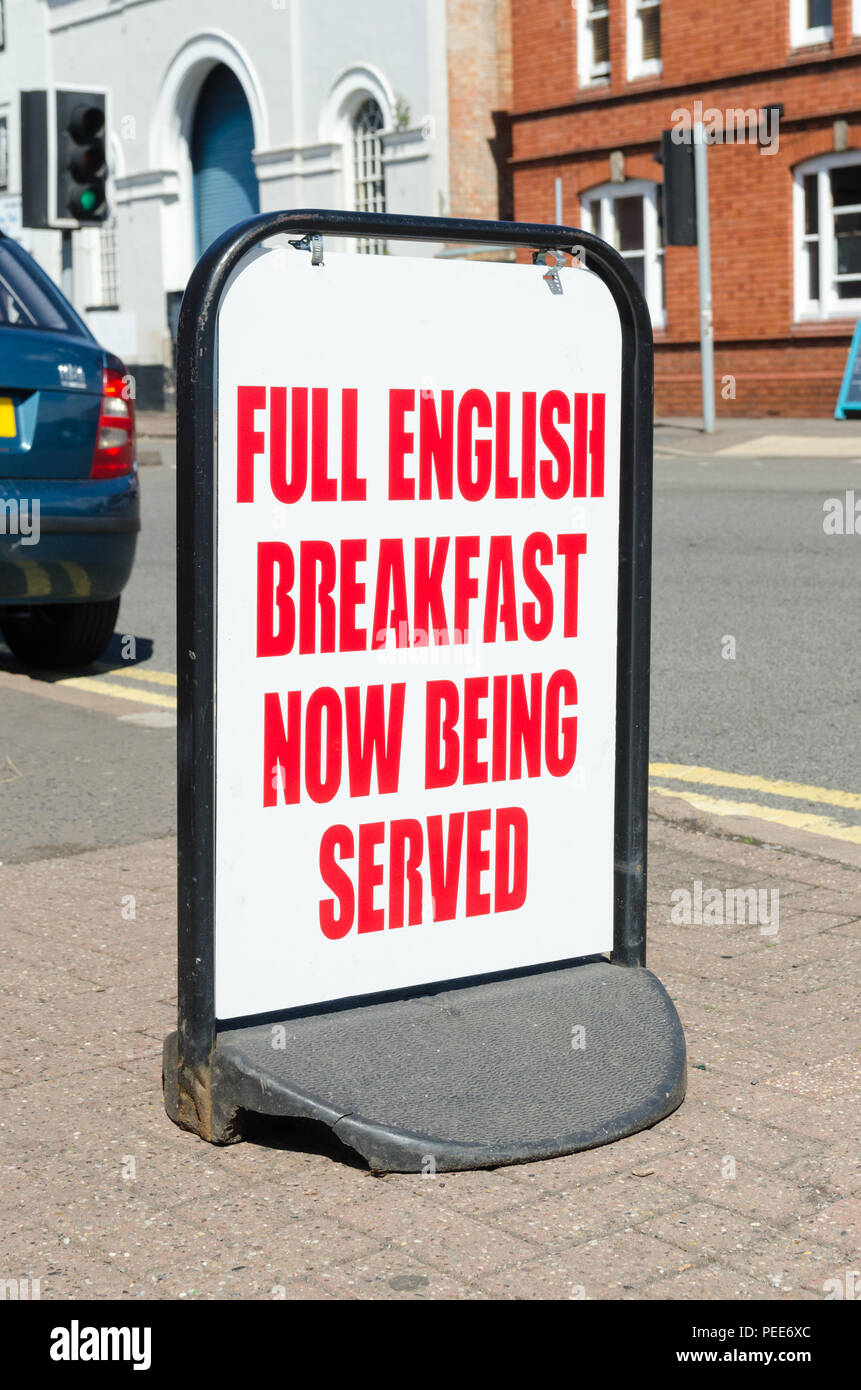 Large red and white freestanding sign outside cafe saying 'full english breakfast now being served' Stock Photo