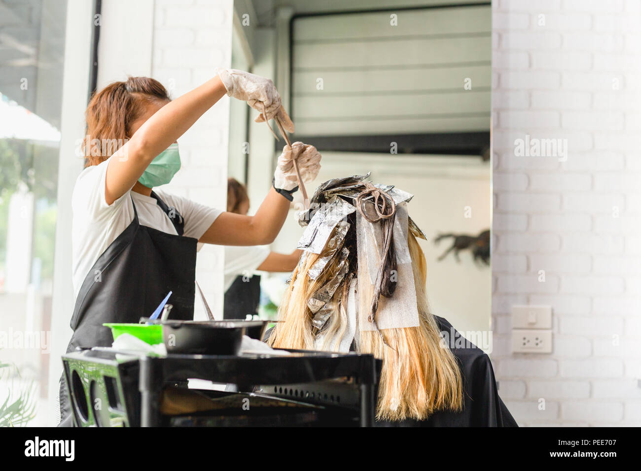 Hairdresser is dying female hair with foil in salon Stock Photo Alamy