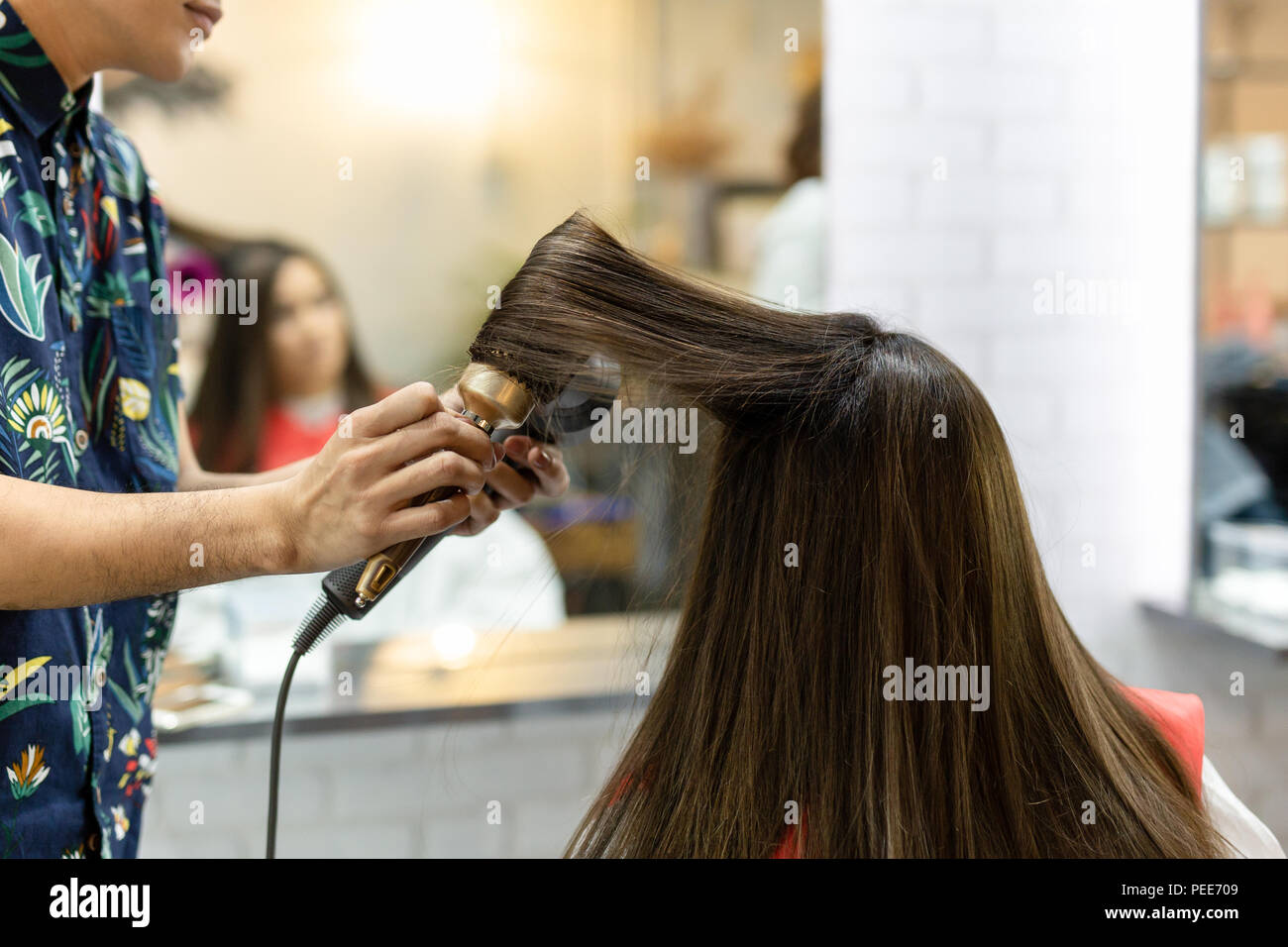 Stylist hairdresser making hairstyle using hair dryer blowing on