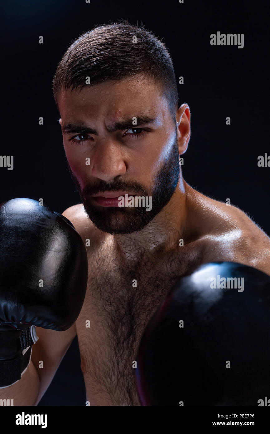 Portrait of tough male boxer posing in boxing stance against black  background Stock Photo - Alamy