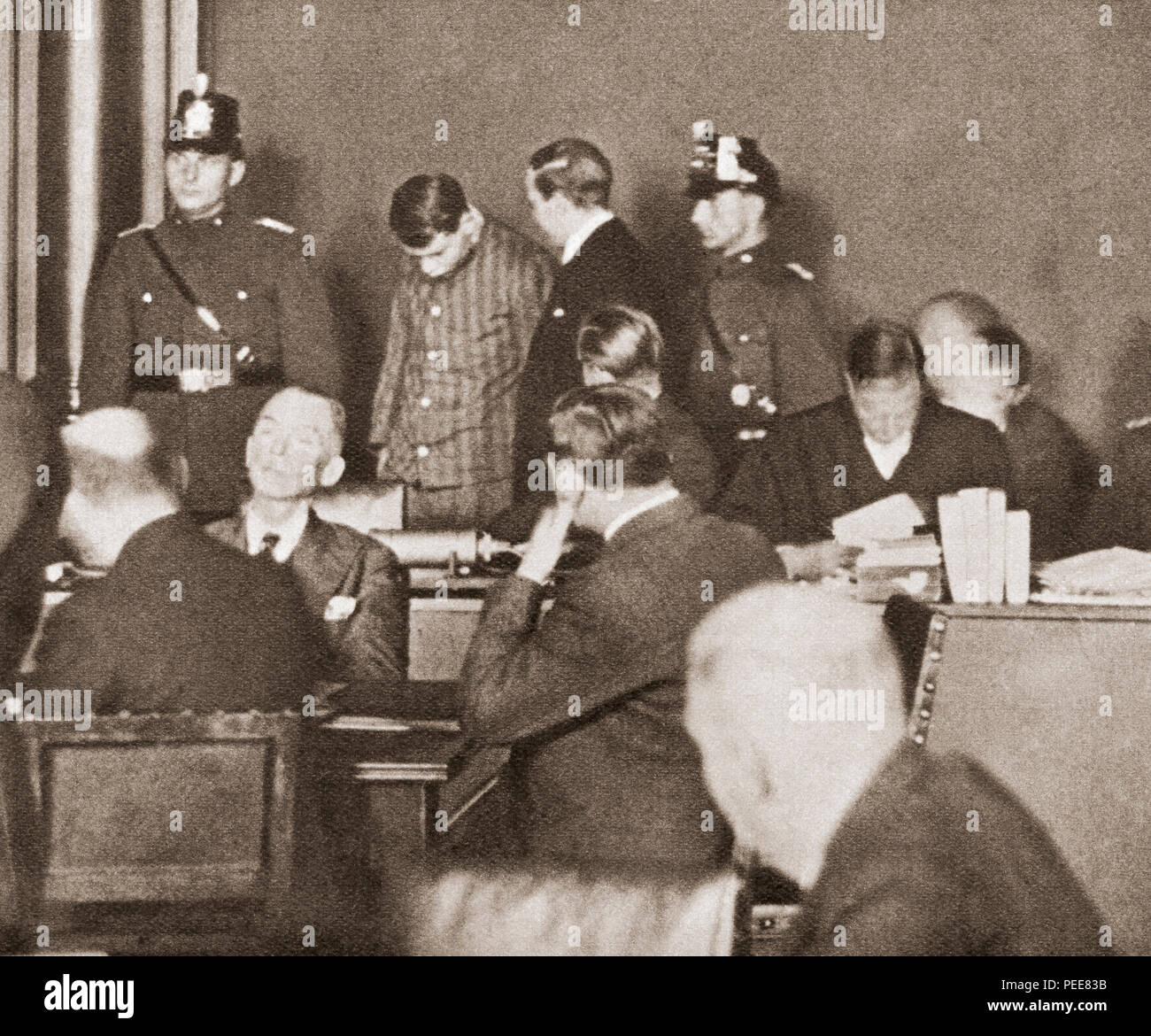 Marinus (Rinus) van der Lubbe, 1909 – 1934.  Dutch council communist tried, convicted and executed for setting fire to the German Reichstag building on 27 February 1933.  He is seen here in court, wearing a convict uniform and with his head bowed.  From These Tremendous Years, published 1938. Stock Photo