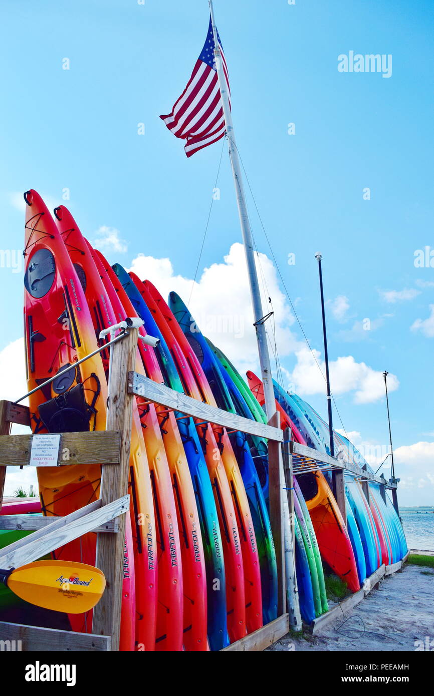 Kayak and boat rental beach side with Tiki bar and man in background