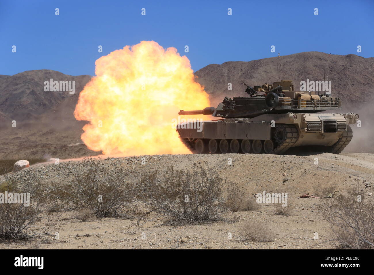 An M1A1 Abrams Main Battle Tank crew with Company A, 4th Tank Battalion, fires its 120 mm main gun during the company’s pre-qualification tank gunnery at Range 500, Aug. 4, 2015. The live-fire exercise tests tank crews on their ability to work together on target acquisition and accuracy. (Official Marine Corps Photo by Lance Cpl. Julio McGraw/Released) Stock Photo