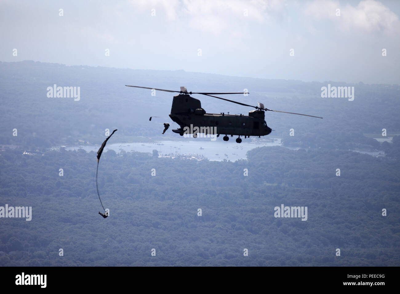 Paratroopers jump from a CH-47 Chinook helicopter for a wing exchange jump at Leapfest in West Kingston, R.I., Aug. 3, 2015. Leapfest is an International parachute competition hosted by the 56th Troop Command, Rhode Island National Guard to promote high level technical training and esprit de corps within the International Airborne community. (U.S. Army Photo by Spc. Josephine Carlson/Released) Stock Photo