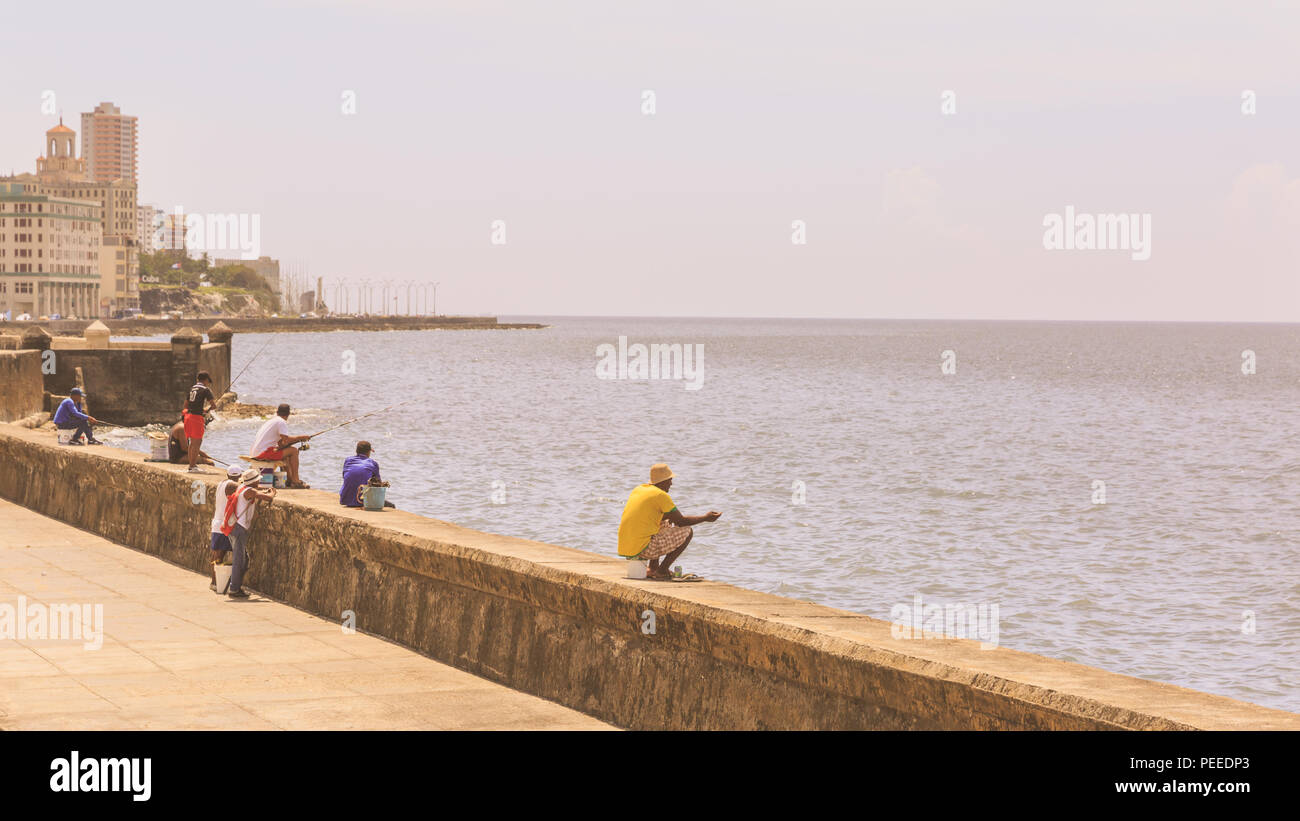 Cuban finshermen, fishing and relaxing by the water along the Malecon seafront boulevard in Havana, Cuba Stock Photo
