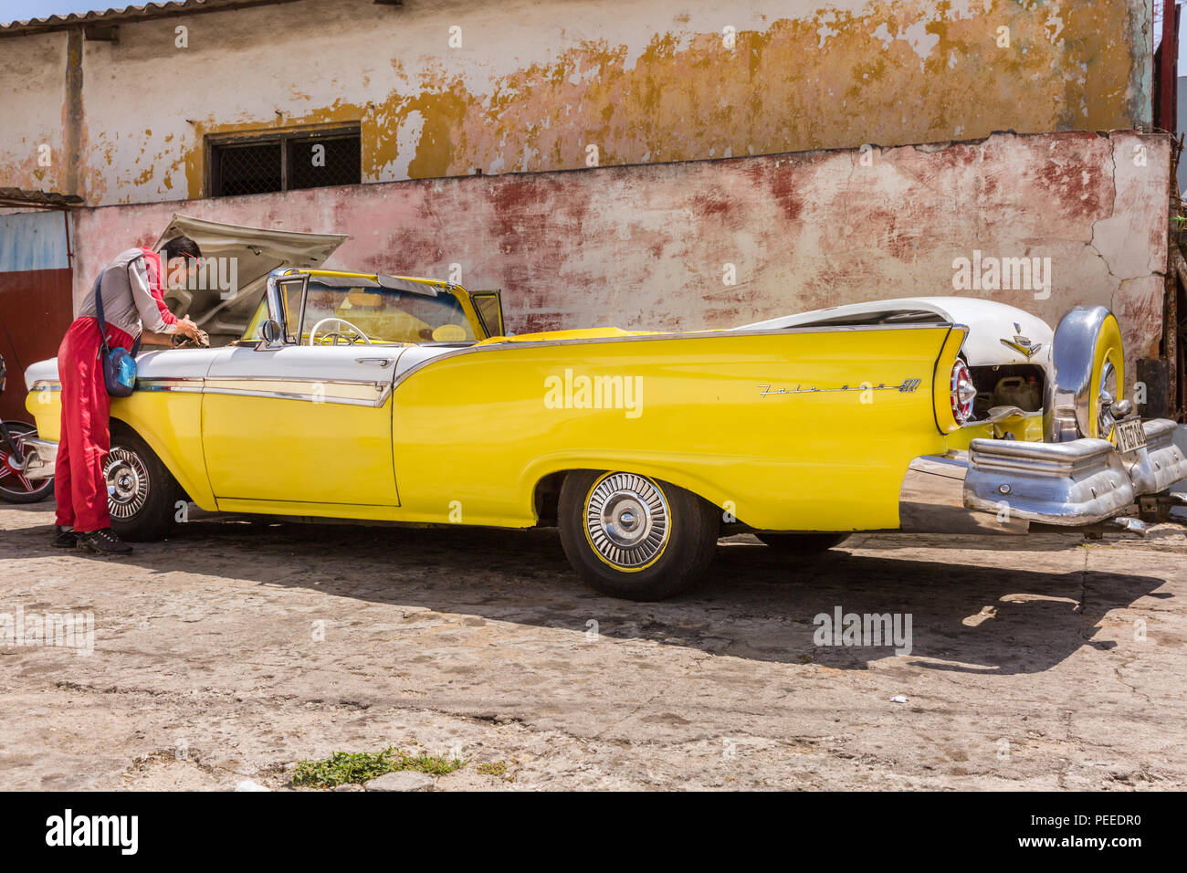 1957 Ford Fairlane 500 Skyliner convertible in yellow, American classic car, mechanic does repair and maintenance at a garage in Havana, Cuba Stock Photo