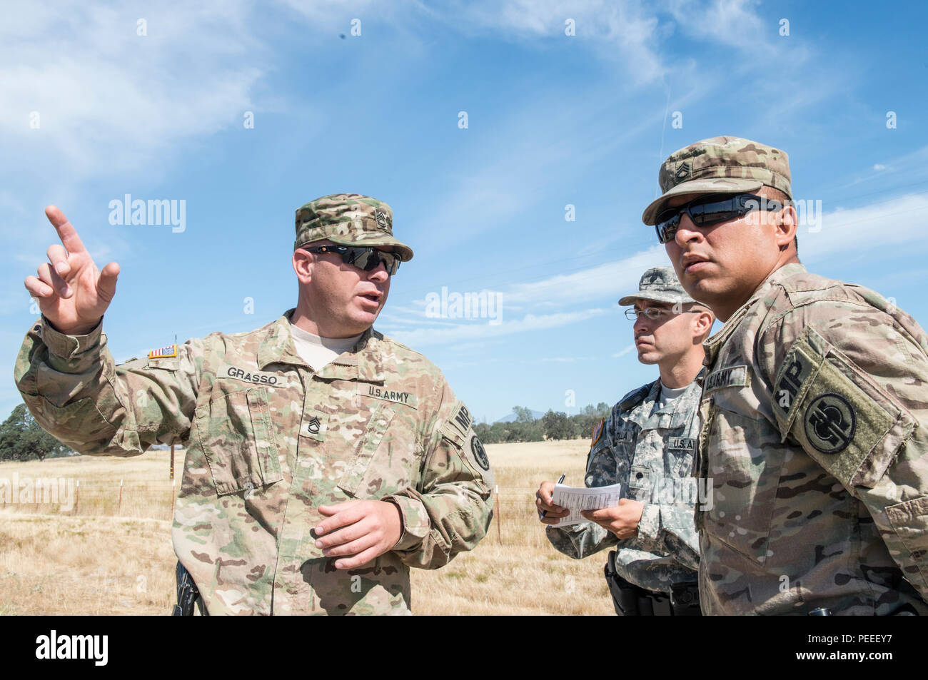 U.S. Army Sgt. 1st Class, Mark Grasso (left), with the 382nd Military Police Detachment, San Diego, gives instructions to military police officers Spc. Juan Padilla (center) from the 382nd Military Police Detachment and Staff Sgt. Daniel Vasquez (right), from the 491st Military Police Company, Riverside, Calif., at Fort Hunter Liggett, Calif., Aug. 3. Grasso, Padilla and Vasquez worked with Fort Hunter Liggett police to maintain law and order, and force protection during their annual training, July 26- Aug. 10. The 382nd supported WAREX 91-15, “Operation Caucasus Restore.” WAREX 91-15 prepares Stock Photo