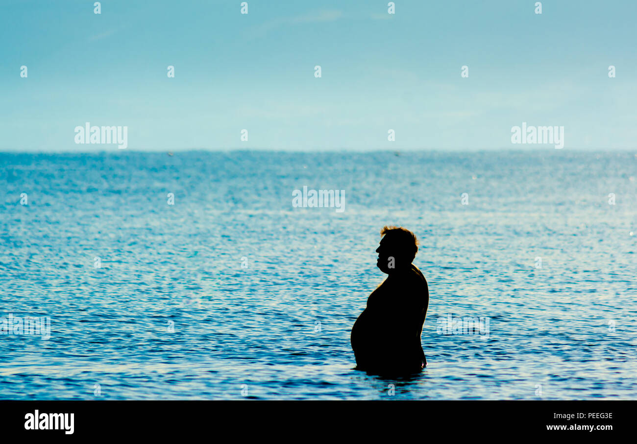 silhouette of fat man in the sea Stock Photo