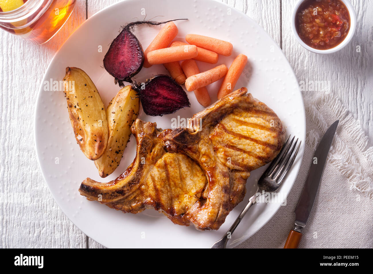 Delicious barbecue grilled pork chops with roasted potato, roasted beets, carrots and relish. Stock Photo