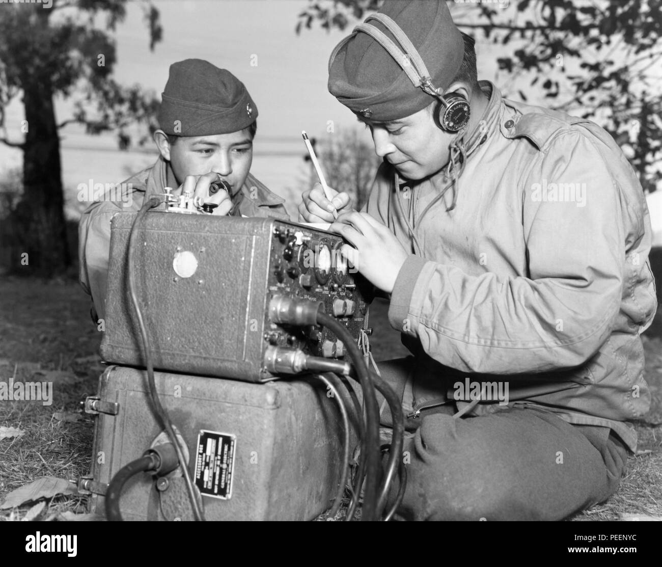 Navajo code talkers, cousins PFC Preston Toledo and PFC Frank Toledo, attached to a Marine Artillery Regiment in the South Pacific during World War II, use a field radio to transmit orders in their native Navajo tongue. Photo: July 7, 1943. Stock Photo