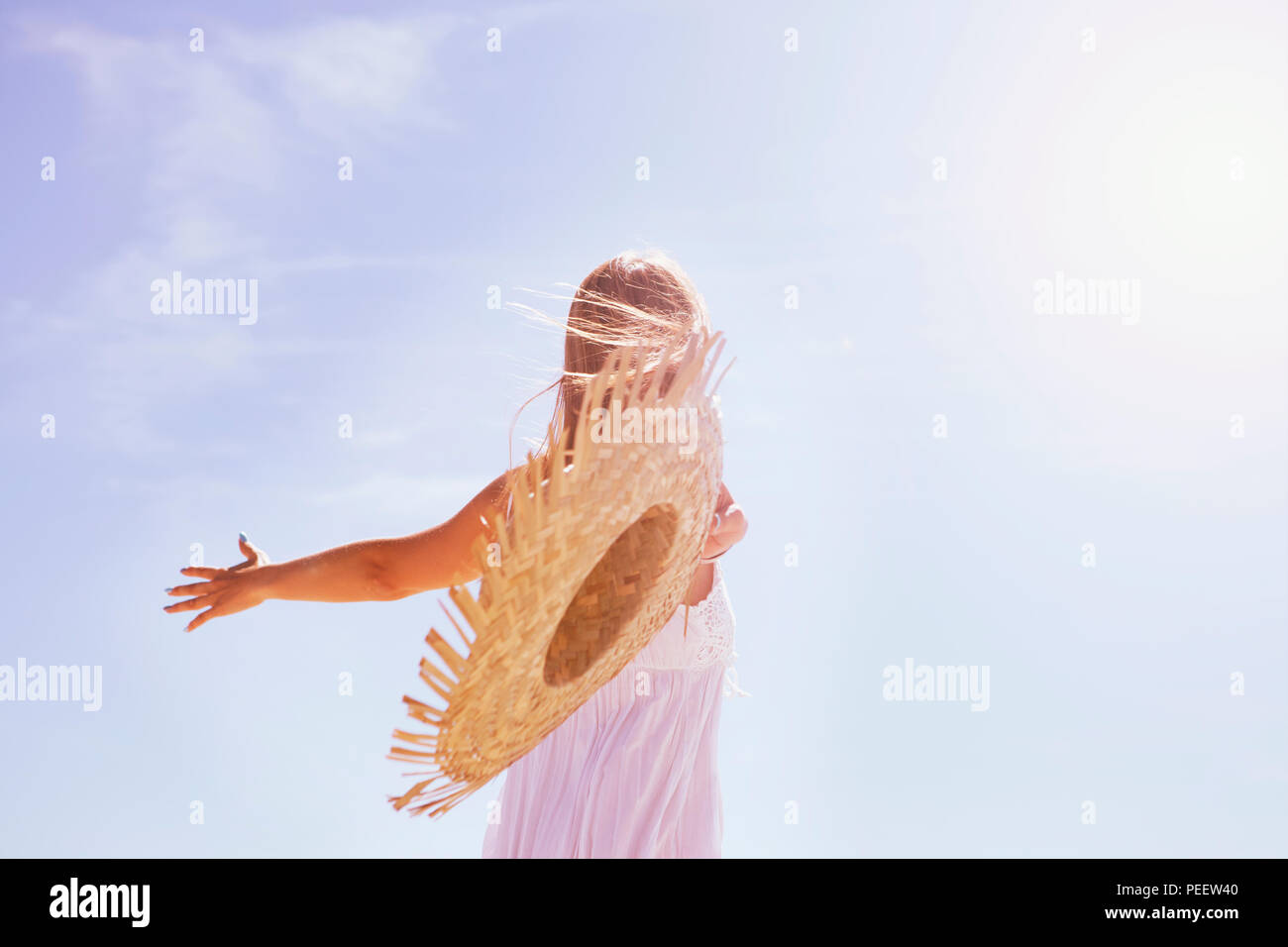 a young woman with long brown hair throws a straw hat in the air Stock Photo