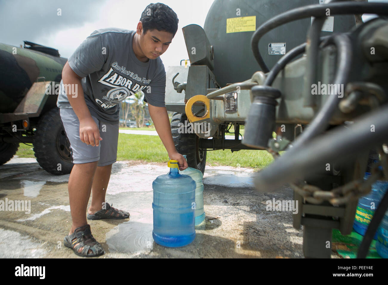 A local man fills up a water jug at a water distribution site set up by U.S. Marines from Combat Logistics Battalion 31, 31st Marin Expeditionary  Unit (MEU), as part of typhoon relief efforts in Saipan, Aug. 11, 2015. The 31st MEU and the ships of the Bonhomme Richard Amphibious Ready Group are assisting the Federal Emergency Management Agency with distributing emergency relief supplies to Saipan after the island was struck by Typhoon Soudelor Aug. 2-3. (U.S. Marine Corps photo by Lance Cpl. Brian Bekkala/Released) Stock Photo