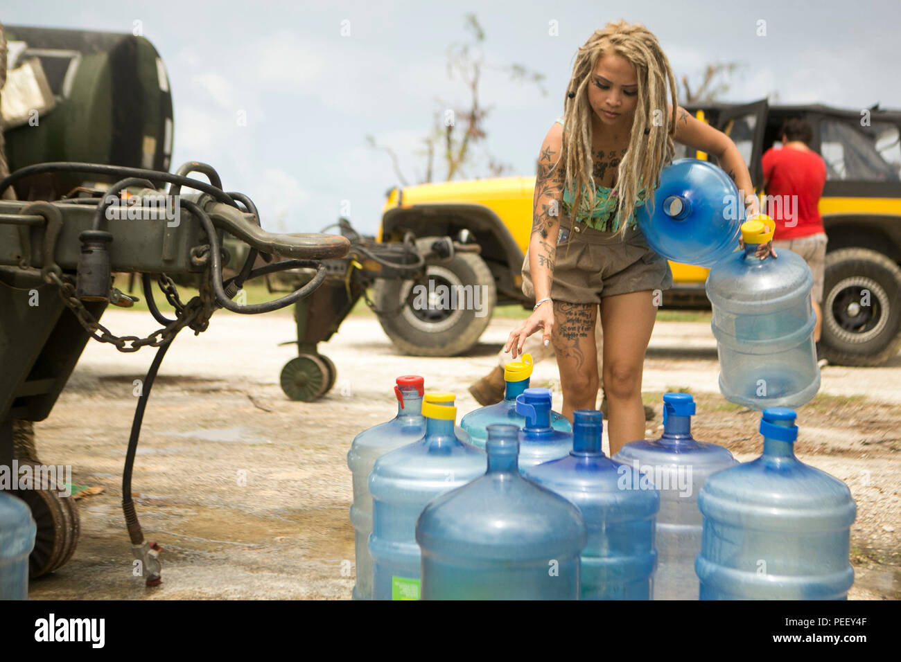 A young woman sets up her water jugs to be filled at a water distribution site set up by U.S. Marines from Combat Logistics Battalion 31, 31st Marine Expeditionary Unit, as part of typhoon relief efforts in Saipan, Aug. 11, 2015. The 31st MEU and the ships of the Bonhomme Richard Amphibious Ready Group are assisting the Federal Emergency Management Agency with distributing emergency relief supplies to Saipan after the island was struck by Typhoon Soudelor Aug. 2-3. (U.S. Marine Corps photo by Lance Cpl. Brian Bekkala/Released) Stock Photo
