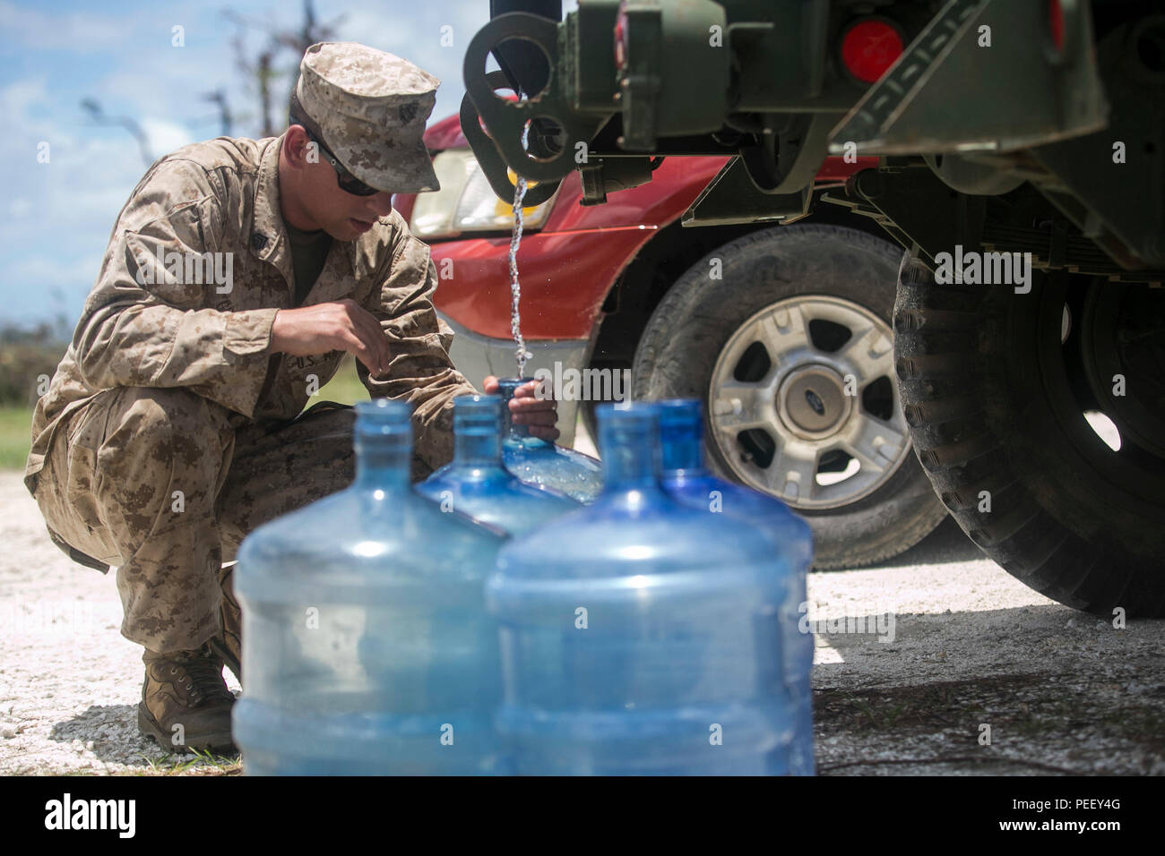 U.S. Marine Sgt. Jeffery Grebbs, with Combat  Logistics Battalion 31, 31st Marine Expeditionary Unit, distributes water to local civilians as part of typhoon relief efforts in Saipan, Aug. 11, 2015. The 31st MEU and the ships of the Bonhomme Richard Amphibious Ready Group are assisting the Federal Emergency Management Agency with distributing emergency relief supplies to Saipan after the island was struck by Typhoon Soudelor Aug. 2-3. (U.S. Marine Corps photo by Lance Cpl. Brian Bekkala/Released) Stock Photo