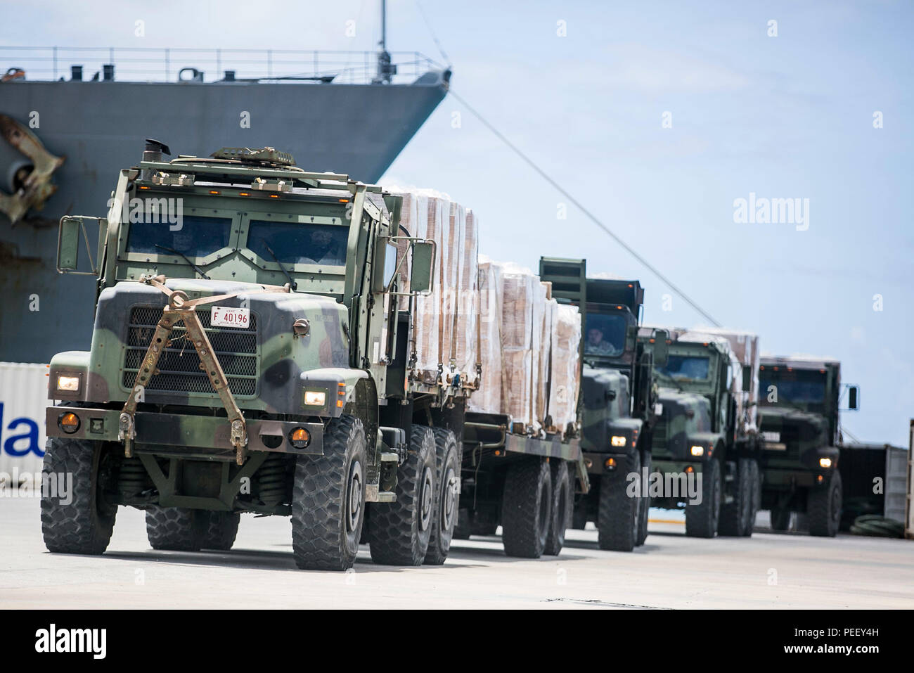 U.S. Marine 7-ton trucks with Combat Logistics Battalion 31, 31st Marine Expeditionary Unit, prepare to distribute water and supplies from the USS Ashland (LSD 48) to local civilians as part of typhoon relief efforts in Saipan, Aug. 11, 2015. The 31st MEU and the ships of the Bonhomme Richard Amphibious Ready Group are assisting the Federal Emergency Management Agency with distributing emergency relief supplies to Saipan after the island was struck by Typhoon Soudelor Aug. 2-3. (U.S. Marine Corps photo by Lance Cpl. Brian Bekkala/Released) Stock Photo
