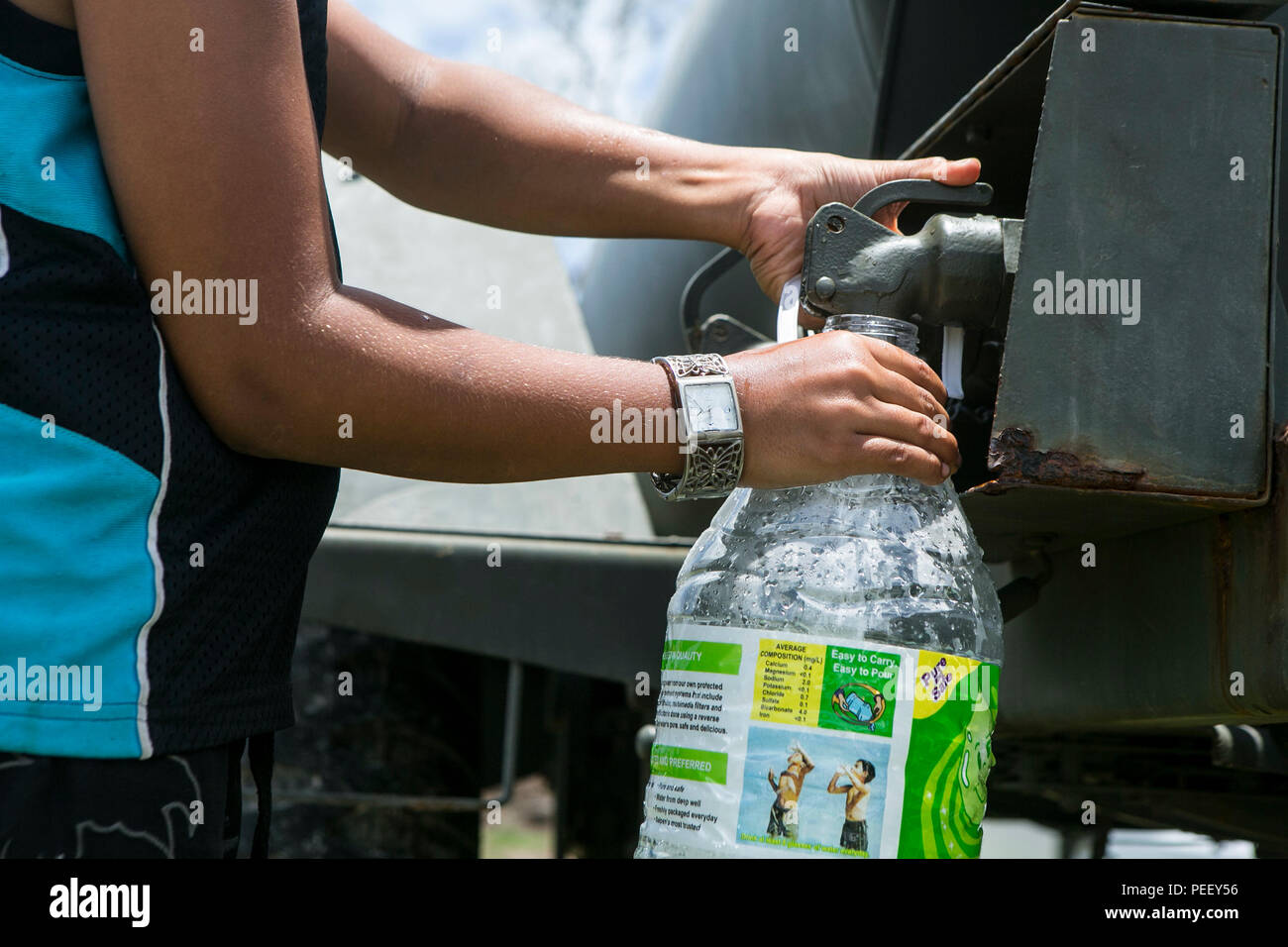 A local boy fills a water jug at a water distribution site set up by U.S. Marines with Combat Logistics Battalion 31, 31st Marine Expeditionary Unit, as part of typhoon relief efforts in Saipan, Aug. 12, 2015. The 31st MEU and the ships of the Bonhomme Richard Amphibious Ready Group are assisting the Federal Emergency Management Agency with distributing emergency relief supplies to Saipan after the island was struck by Typhoon Soudelor Aug. 2-3. (U.S. Marine Corps photo by Lance Cpl. Brian Bekkala/Released) Stock Photo