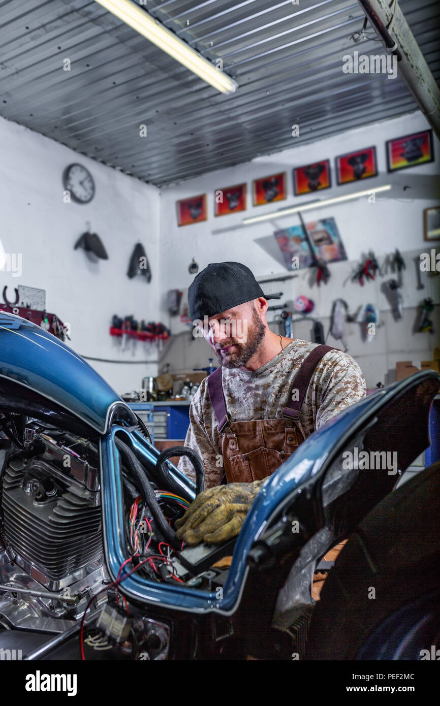 Side View Portrait Of Man Working In Garage Repairing Motorcycle