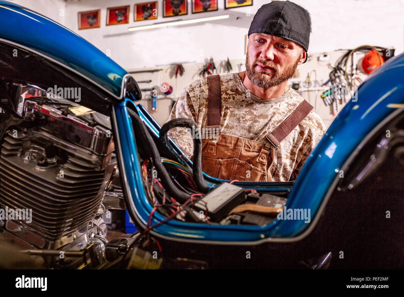 Side View Portrait Of Man Working In Garage Repairing Motorcycle