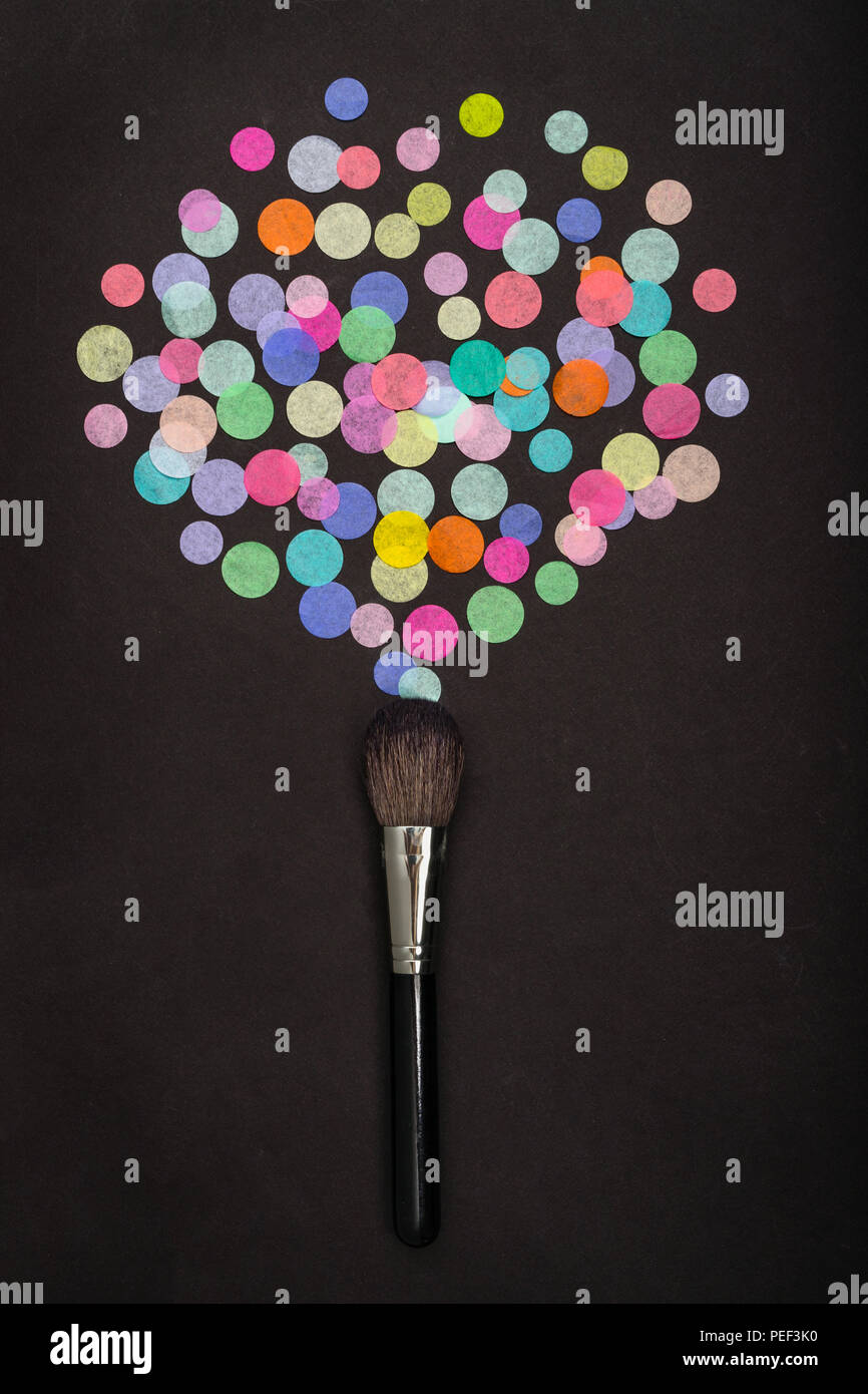 Make-up brush with scattered colorful confetti on black background Stock Photo
