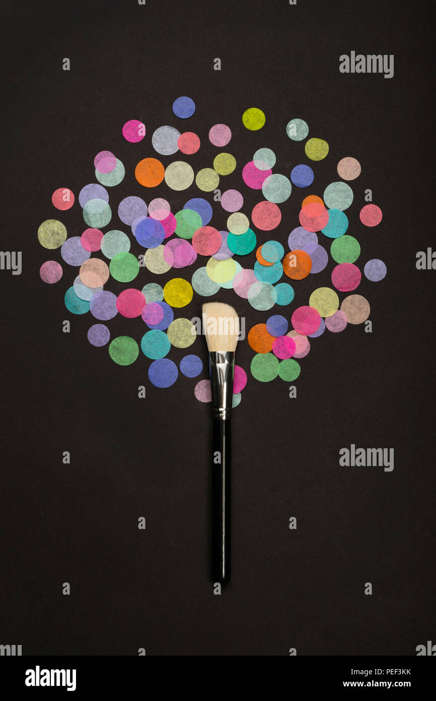 Make-up brush with scattered colorful confetti on black background Stock Photo