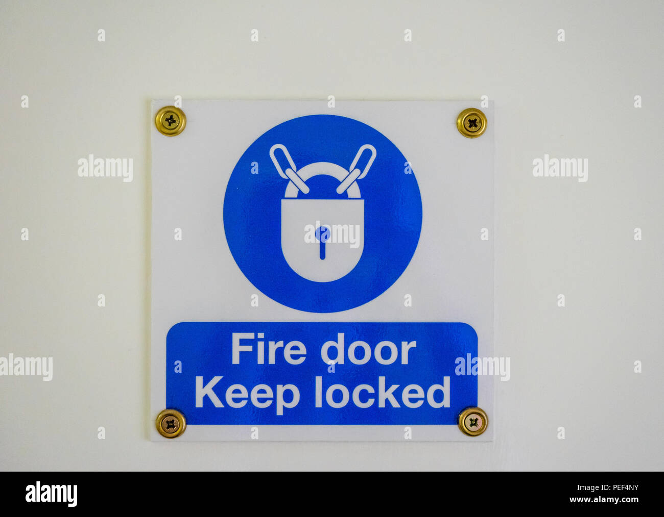 Blue 'Fire door keep locked' sign in a residential block of flats, England, UK Stock Photo