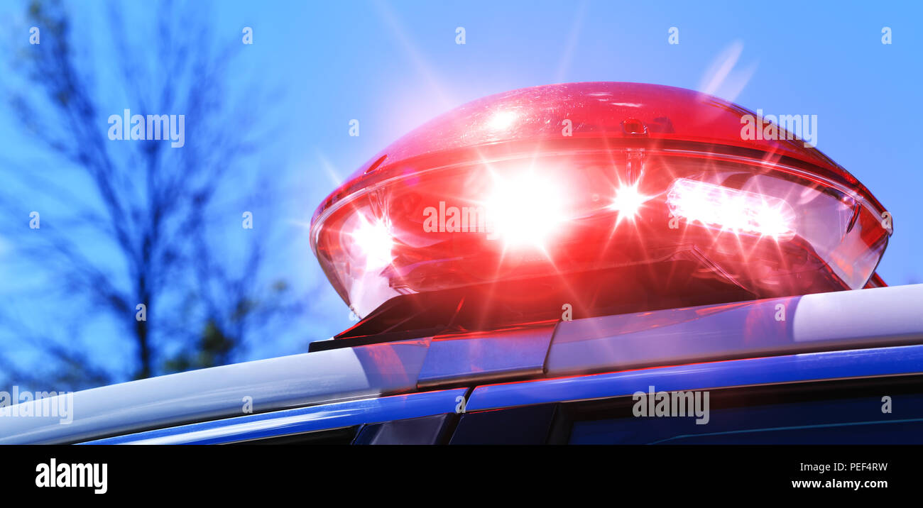Police car with focus on red siren light. Colorful red siren on the roof of a police car in a real intervention. Beautiful red siren lights activated  Stock Photo