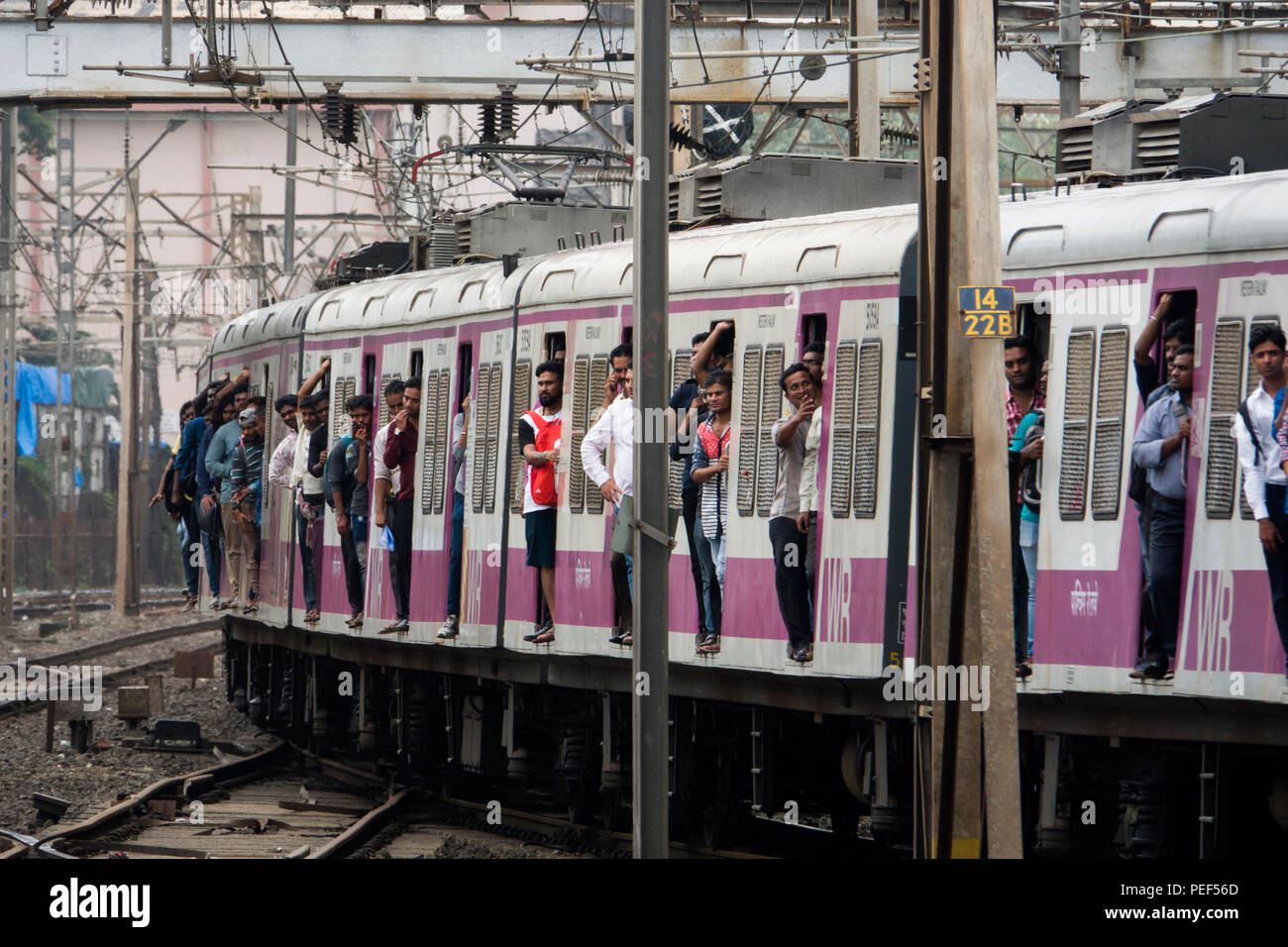 Passengers hanging out of trains door on a Mumbai Suburban Railway train arriving at Bandra