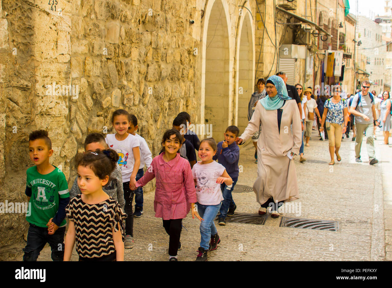 10 May 2018 A group of young children and their female Muslam guardian in traditional modest dress walking in the old city of Jerusalem Israel Stock Photo