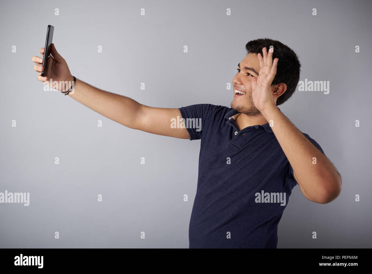 Young man wave hand into videop call in studio background Stock Photo
