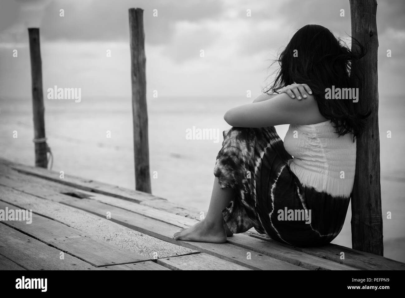 Black And White Of Sad And Lonely Woman Sitting Alone On A The Wooden Bridge Over The Sea Stock Photo Alamy