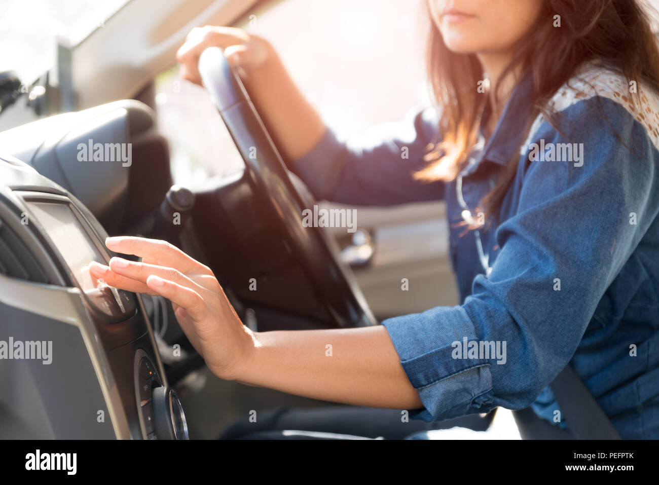 woman driver hand touching the screen entering an address into the navigation system and turning on car radio system. Stock Photo