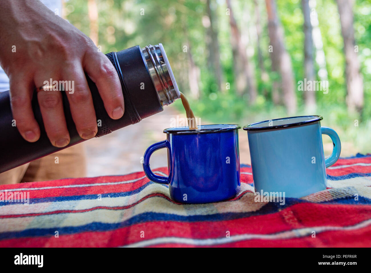 man hand pour on coffee into metal cups from thermos bottle. copy space Stock Photo