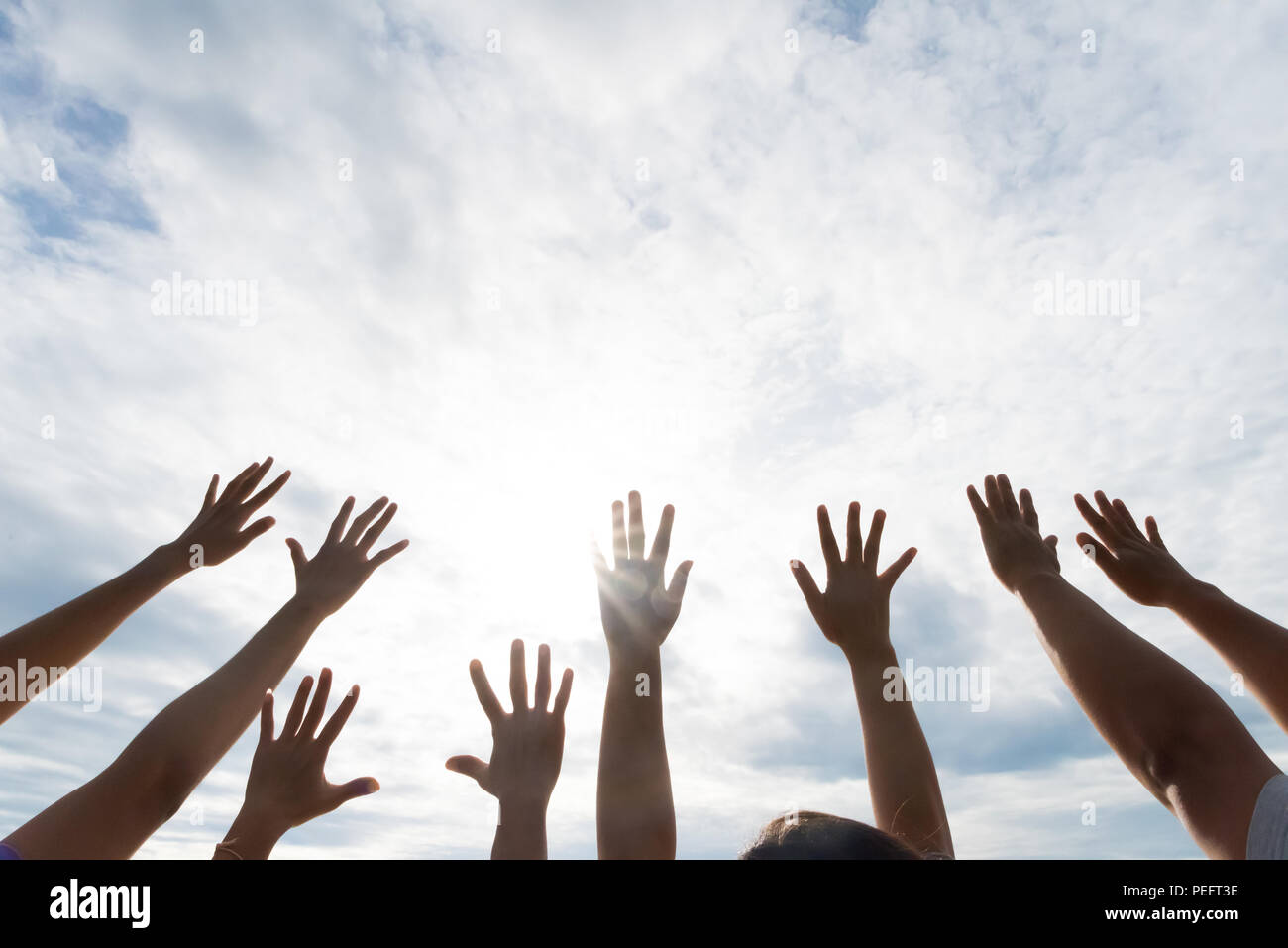 Many hands raised up against the blue sky. Friendship, Teamwork concept. Stock Photo