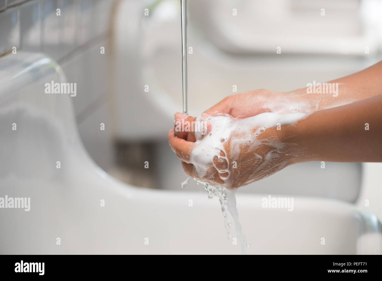 Closeup woman washing hands with soap under the faucet with water in ...