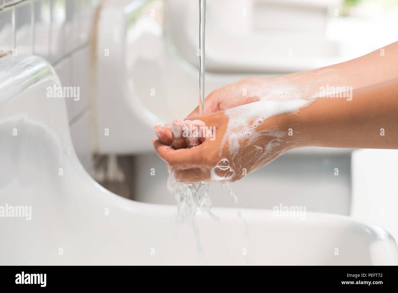 Closeup woman washing hands with soap under the faucet with water in ...