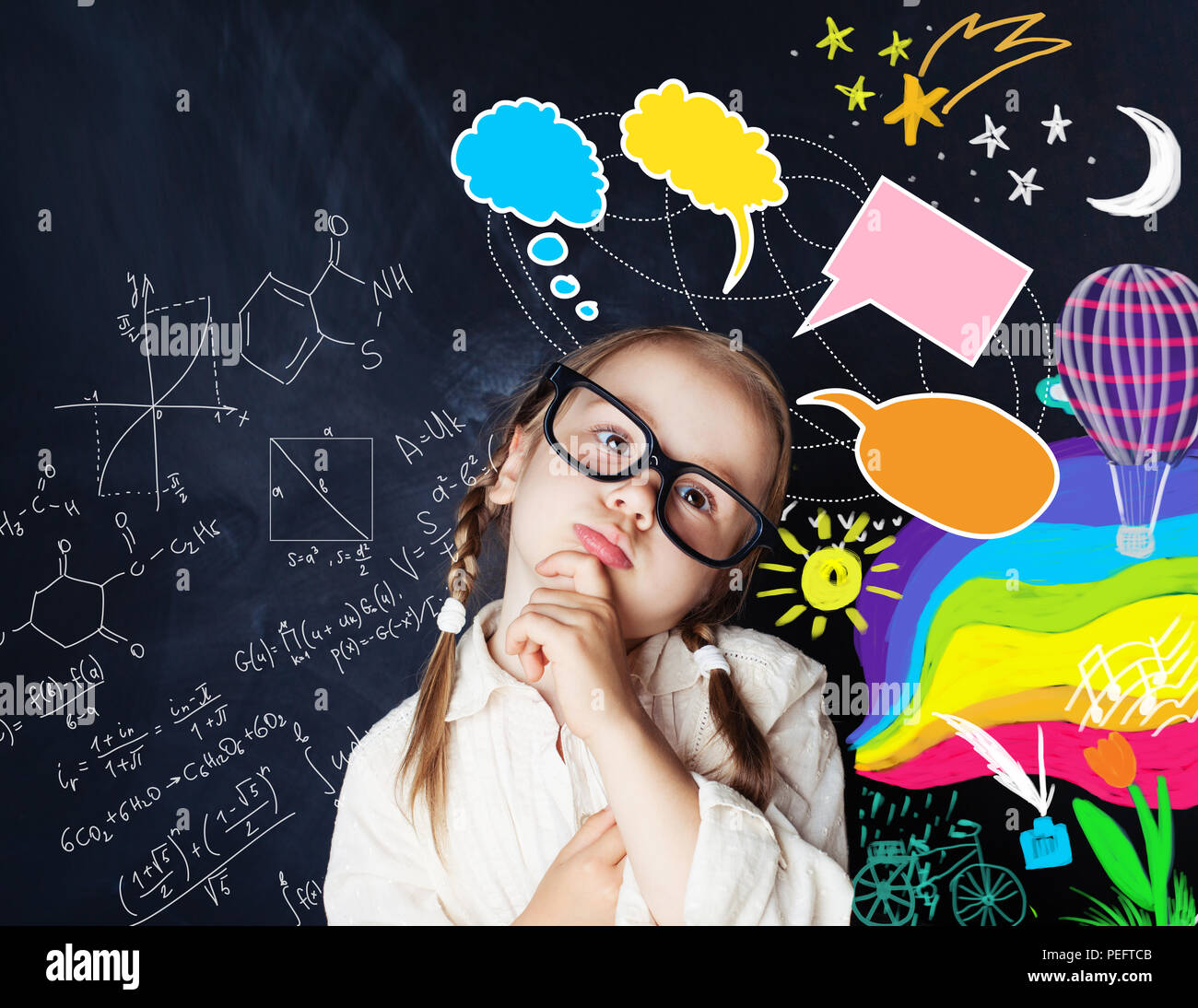 Smart kid with speech bubbles and colorful creative design elements and science formulas on chalk board Stock Photo