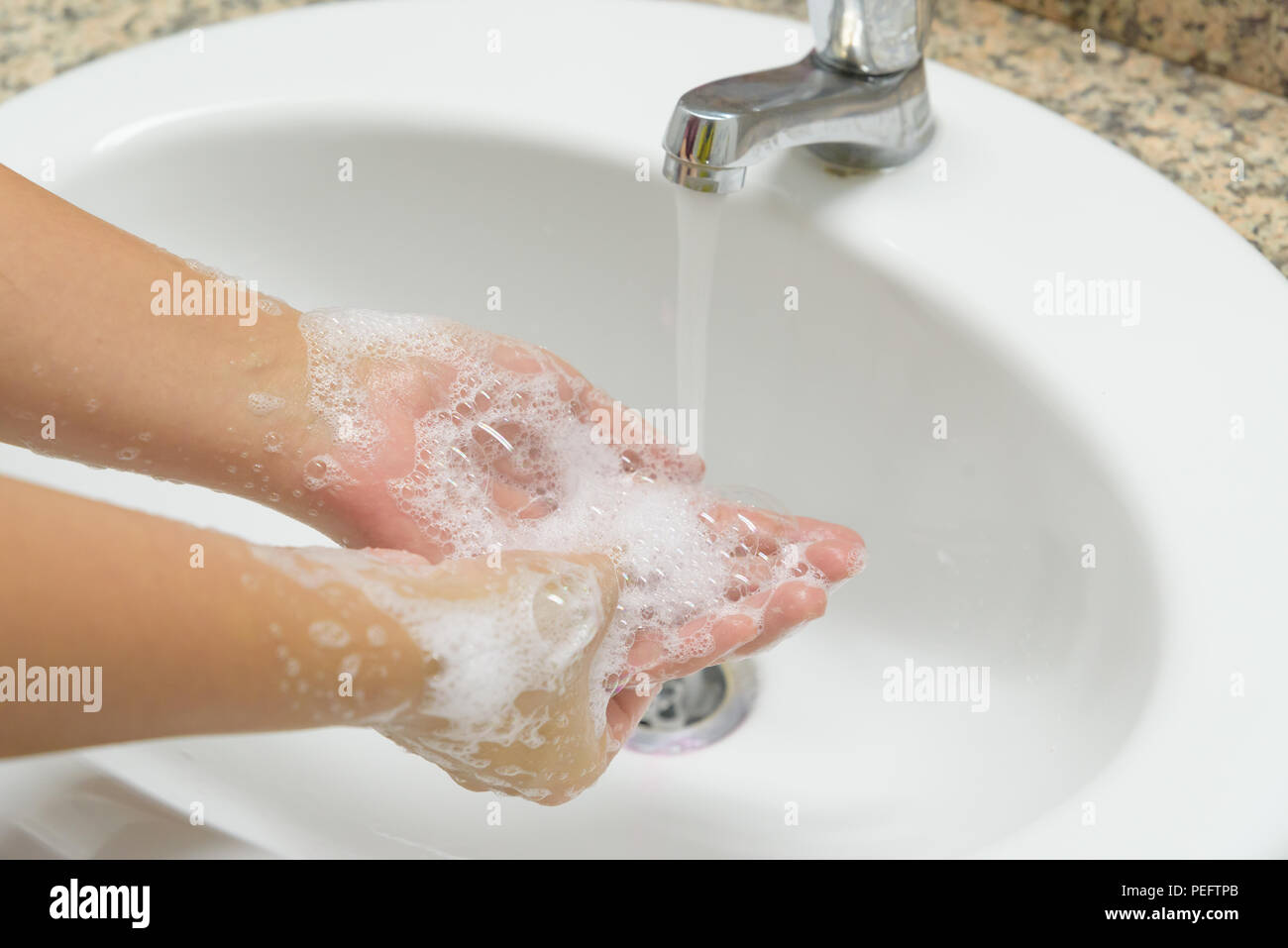 Closeup woman washing hands with soap under the faucet with water in ...