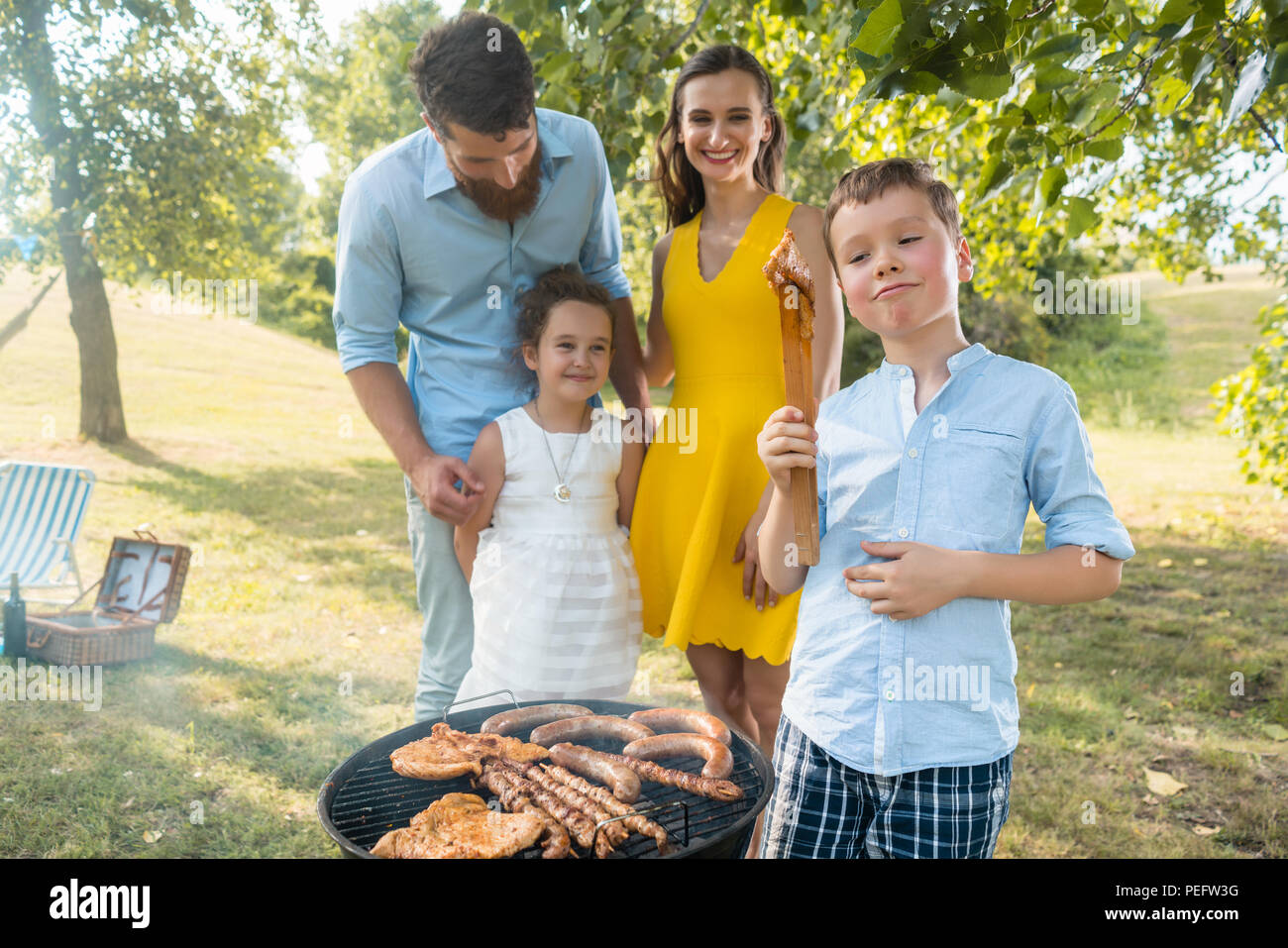 Portrait of happy family with two children standing outdoors near a barbecue Stock Photo
