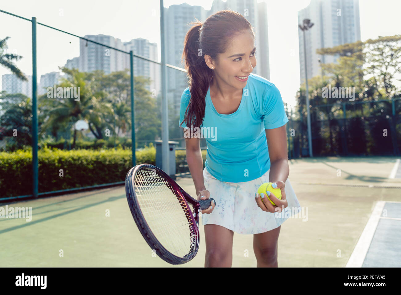 Professional female player smiling while serving during tennis match Stock Photo