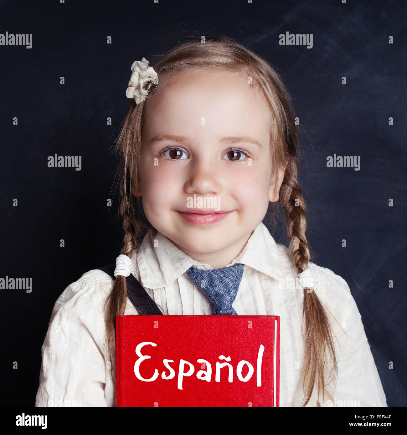 Kid learning spanish in language school. Happy little girl holding book