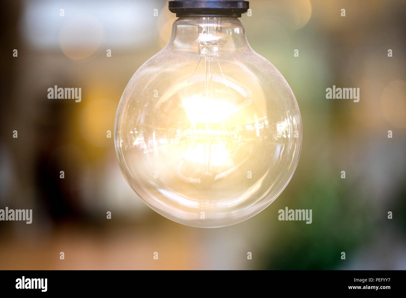 Hanging incandescent light bulb on defocus background Stock Photo - Alamy