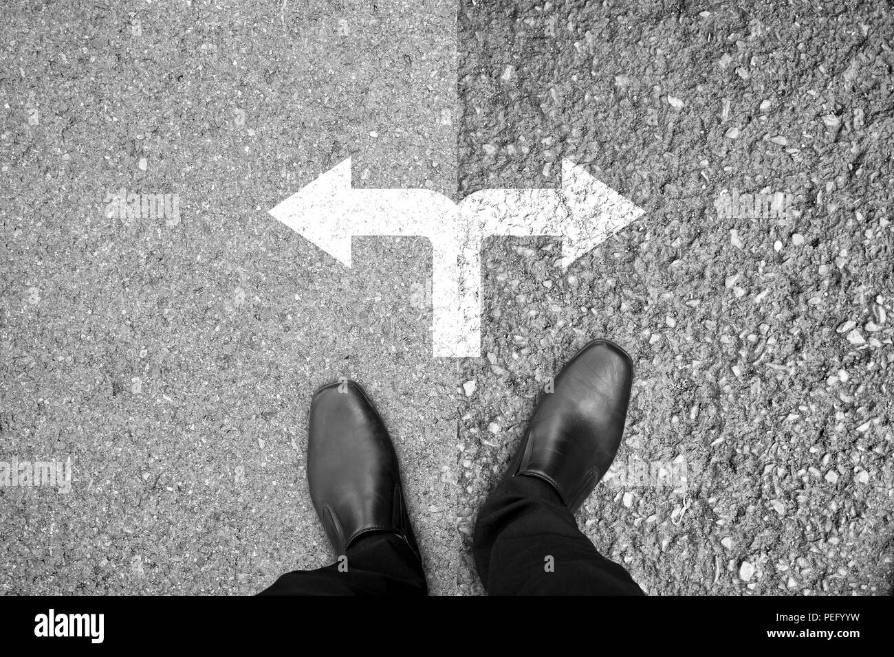 Businessman in black shoes standing at the crossroad making decision which way to go - easy or hard Stock Photo