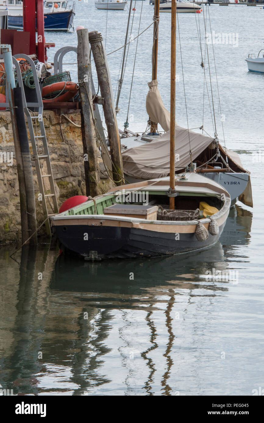 an old or traditional sailing dinghy alongside a wall in the harbour at