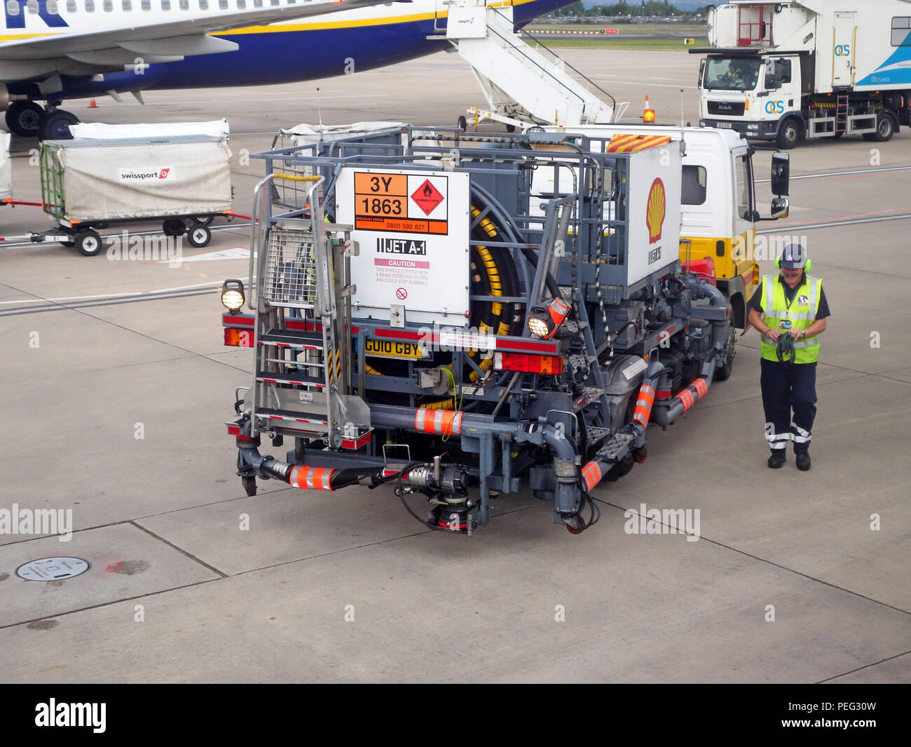 Airport worker starting the aviation refuelling of a plane at Manchester International Airport. image shows a fuel truck with plane also in shot Stock Photo