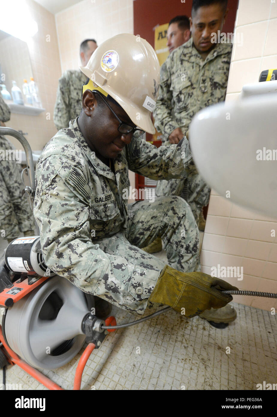 150818-N-SD120-006 OKINAWA, Japan (Aug. 18, 2015) Utilitiesman 3rd Class Kevin Galbert, from Wichita, Kan., uses an electric auger, commonly referred to as a plumbing snake, to clear a clogged drain in Naval Mobile Construction Battalion (NMCB) 5’s headquarters building on Camp Shields, Okinawa. NMCB 5 is currently deployed to Japan and several countries in the Pacific area of operations conducting construction operations and humanitarian assistance projects. (U.S. Navy photo by Mass Communication Specialist 1st Class John P. Curtis/Released) Stock Photo