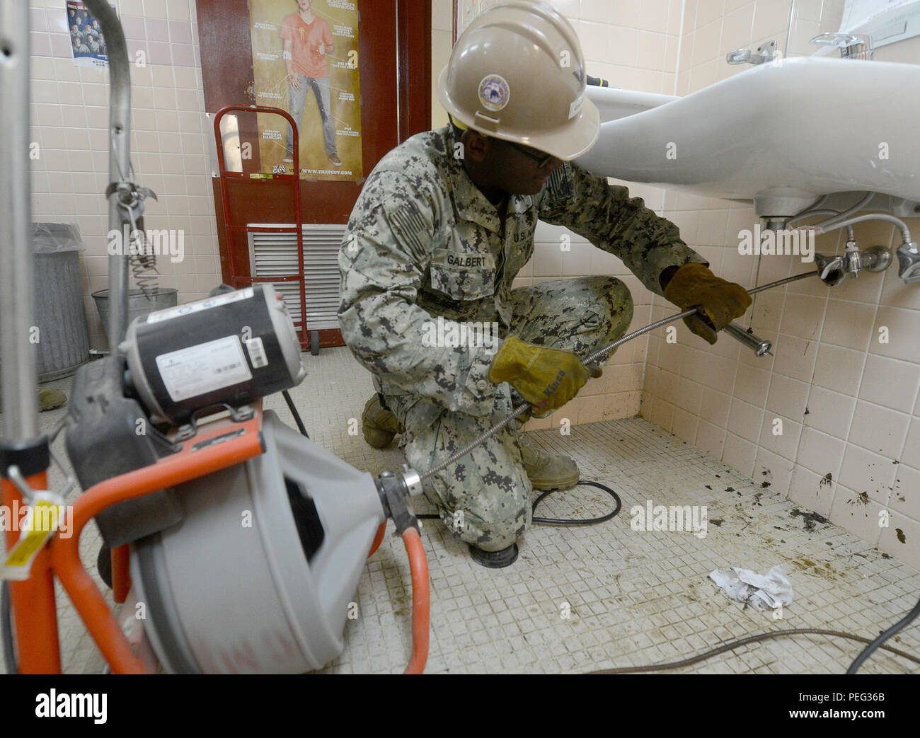 150818-N-SD120-007 OKINAWA, Japan (Aug. 18, 2015) Utilitiesman 3rd Class Kevin Galbert, from Wichita, Kan., uses an electric auger, commonly referred to as a plumbing snake, to clear a clogged drain in Naval Mobile Construction Battalion (NMCB) 5’s headquarters building on Camp Shields, Okinawa. NMCB 5 is currently deployed to Japan and several countries in the Pacific area of operations conducting construction operations and humanitarian assistance projects. (U.S. Navy photo by Mass Communication Specialist 1st Class John P. Curtis/Released) Stock Photo