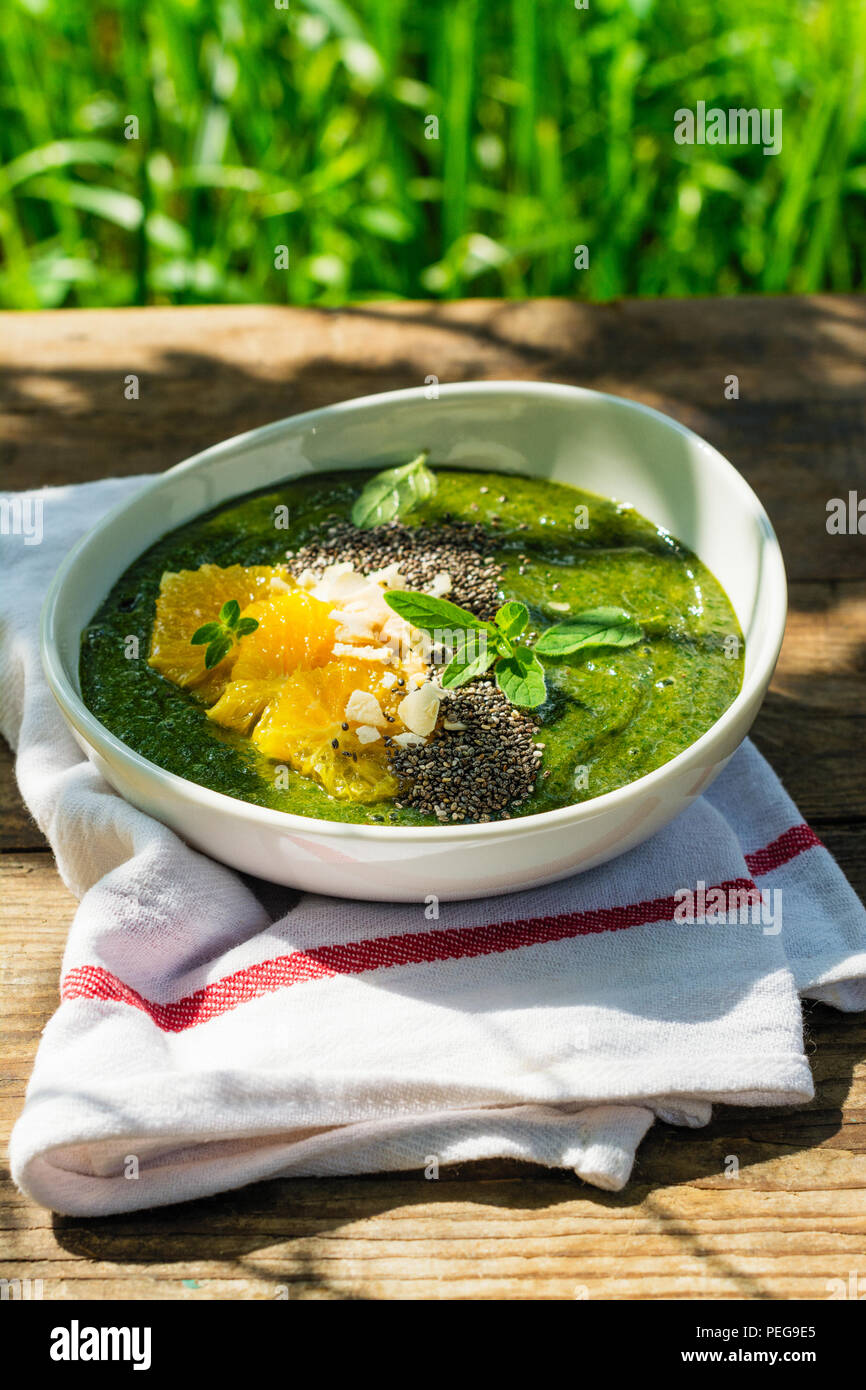 Green smoothie bowl with banana, spinach, chia seeds and oranges Stock