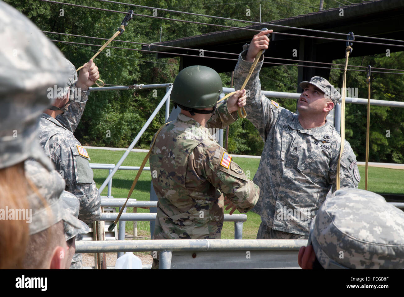 U.S. Army Staff Sgt. Angel Cotte, safety for primary Jumpmaster from Echo Co.1-507th Airborne Infantry Battalion demonstrates  correct  static line hook-up procedures during sustained Airborne training in preparation for the 75th Anniversary Airborne School jump, on Fort Benning, Ga. Aug. 14, 2015. The 1-507th Parachute Infantry Regiment(PIR) Battalion and the 982nd Combat Camera celebrates 75 years of the U.S. Army Airborne School and the commemoration of the last qualifying jump of the first airborne test platoon on Aug. 15, 1940. (U.S. Army photo by Spc. Charles M. Willingham/ Released) Stock Photo